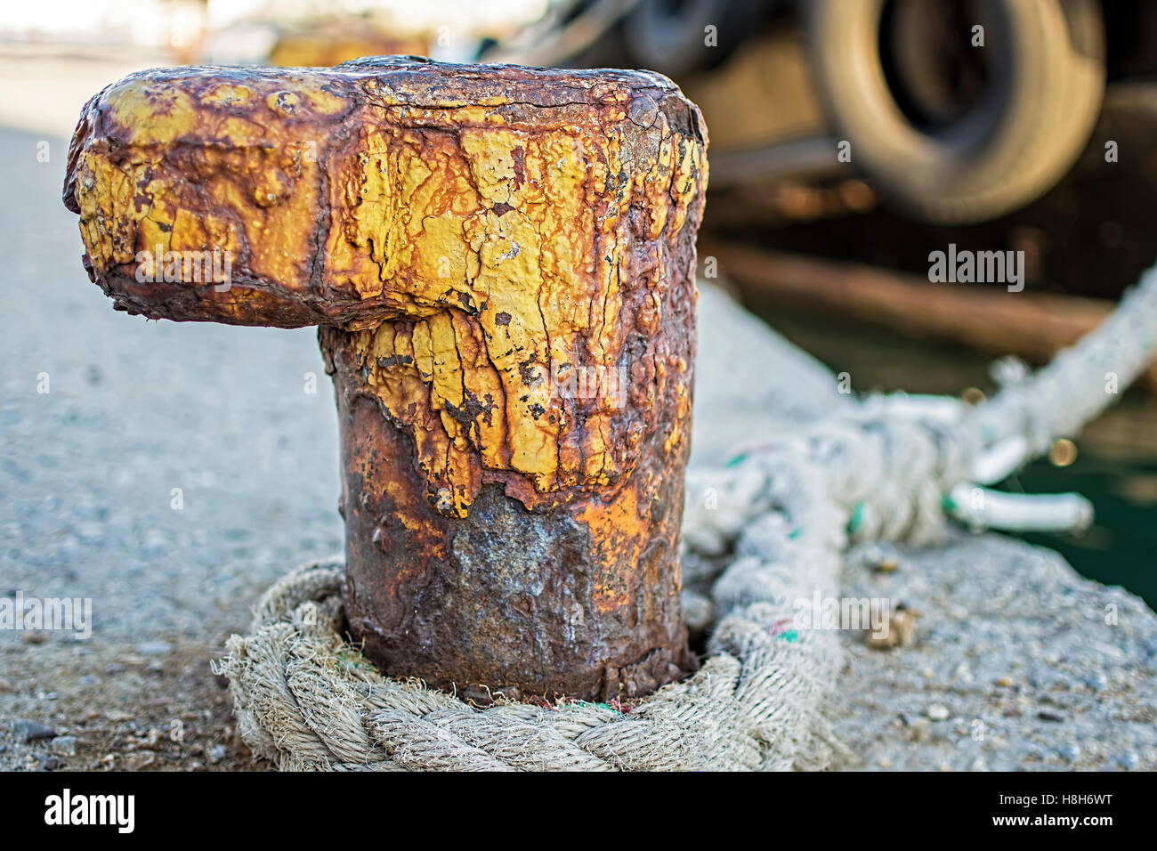 Alte rostige Poller mit ausgefransten Schiff Seil am Hafen. Nautische Hintergrund. Stockfoto