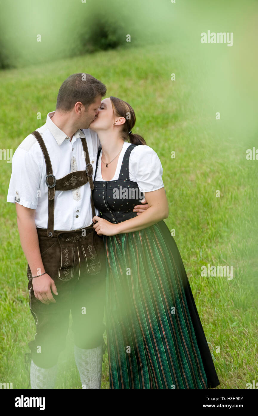 Junges Paar in Tracht, küssen auf einer Wiese Stockfoto