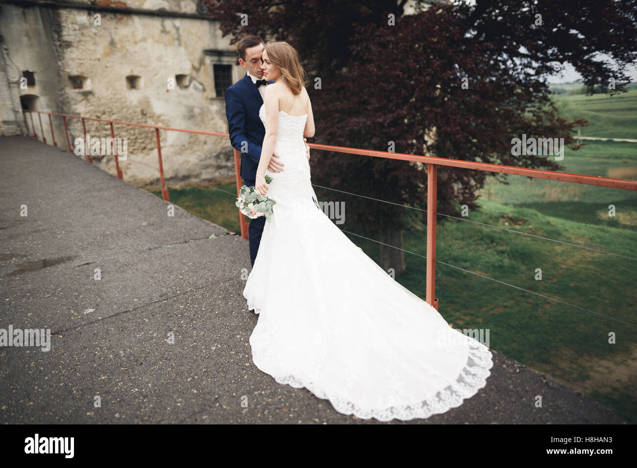 Glückliche Hochzeit paar umarmt und lächelnd einander auf Hintergrund altes Schloss Stockfoto