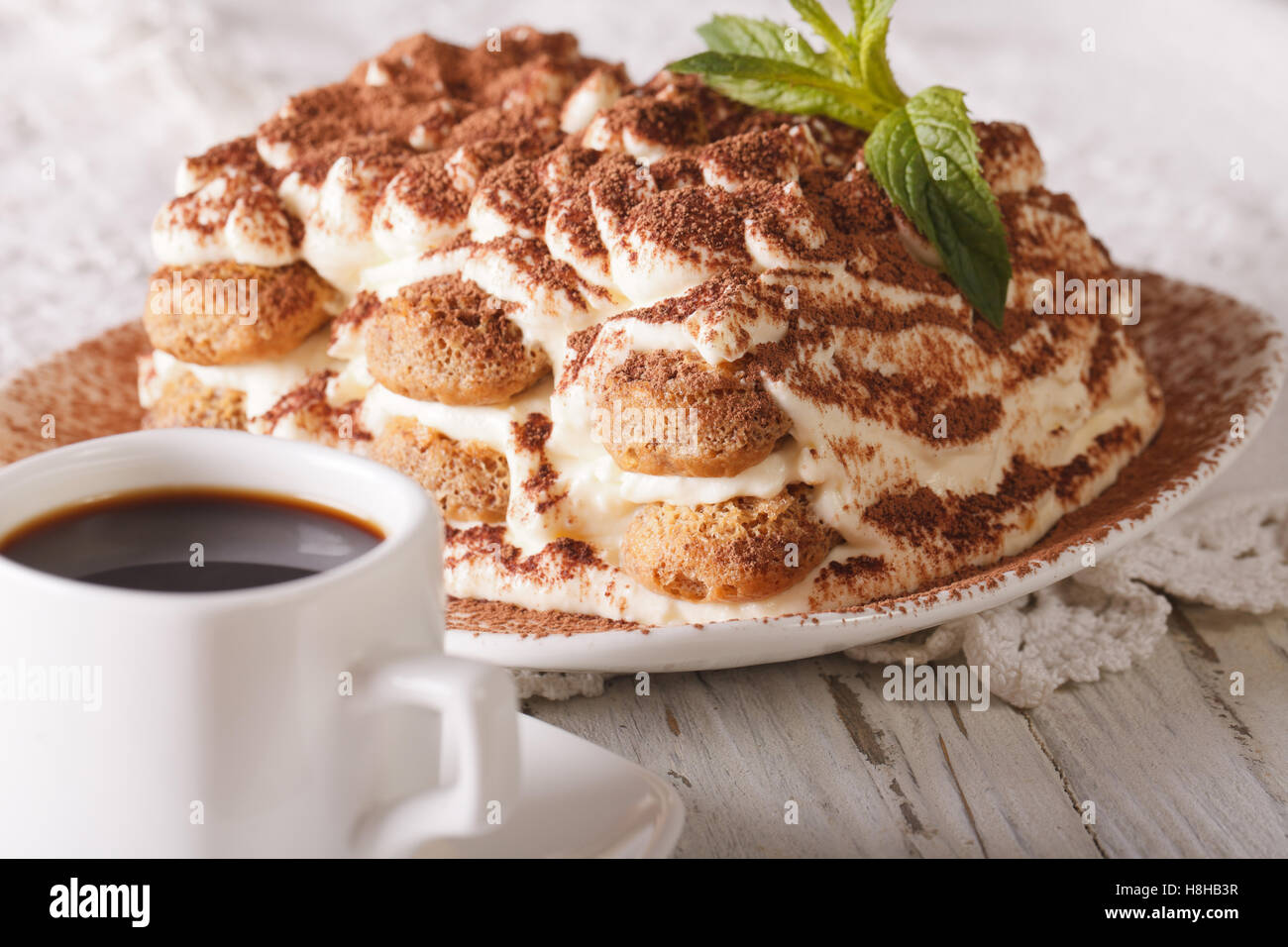 Italienisches Tiramisu-Kuchen auf einen Teller und Tasse schwarzen Kaffee auf den Tisch-Nahaufnahme. Horizontale Stockfoto