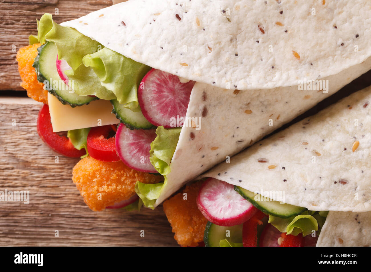 Burrito mit Fischstäbchen und Gemüse Makro auf dem Tisch. horizontale Ansicht von oben Stockfoto