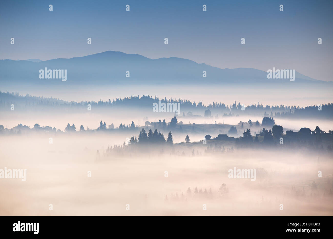 Nebligen Herbstmorgen in Karpaten. Alpine Dorf auf den Hügeln Stockfoto