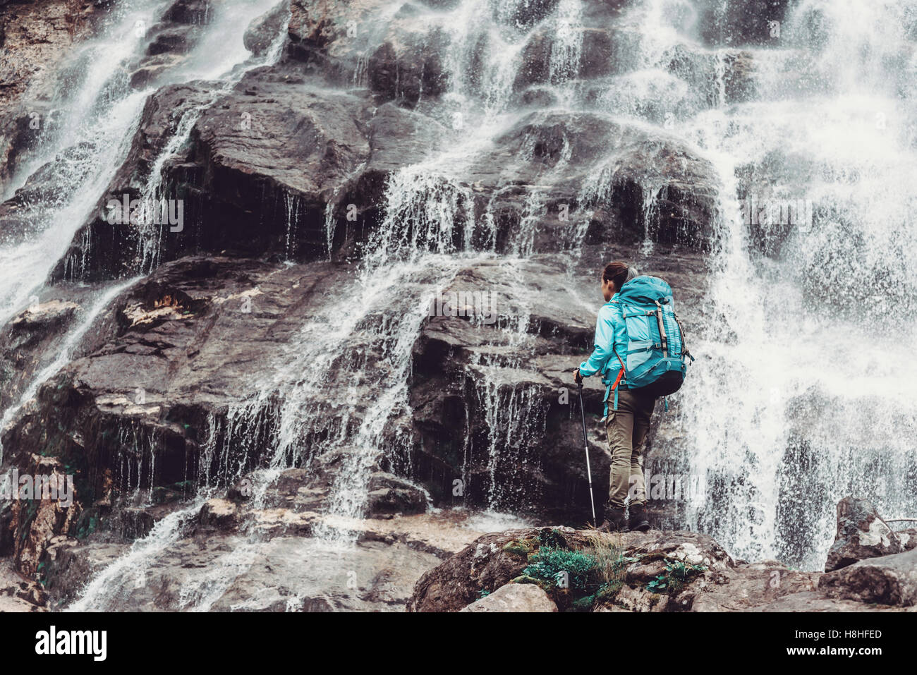 Backpacker junge Frau stehend mit trekking-Stöcke auf Stein und mit Blick auf schöne Wasserfall Stockfoto