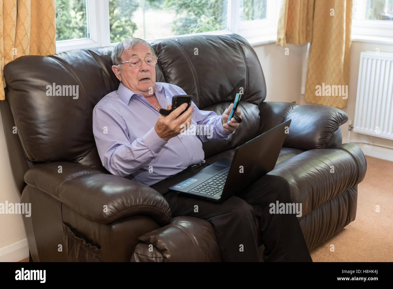Rentner versucht, moderne elektronische Geräte wie Laptop und Handy zu verwenden. Stockfoto
