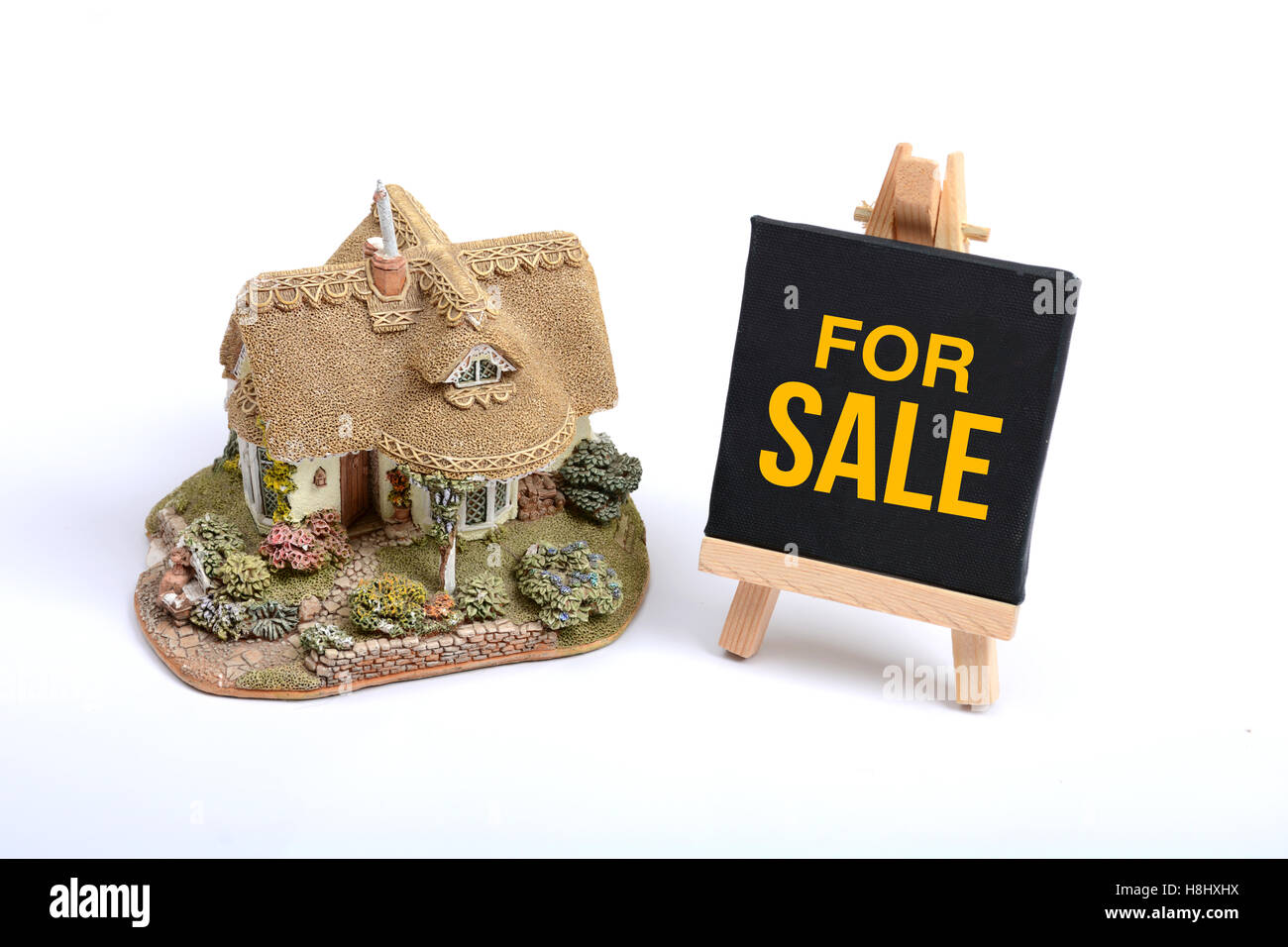 Miniaturhaus mit For Sale Schild White Background. Stockfoto