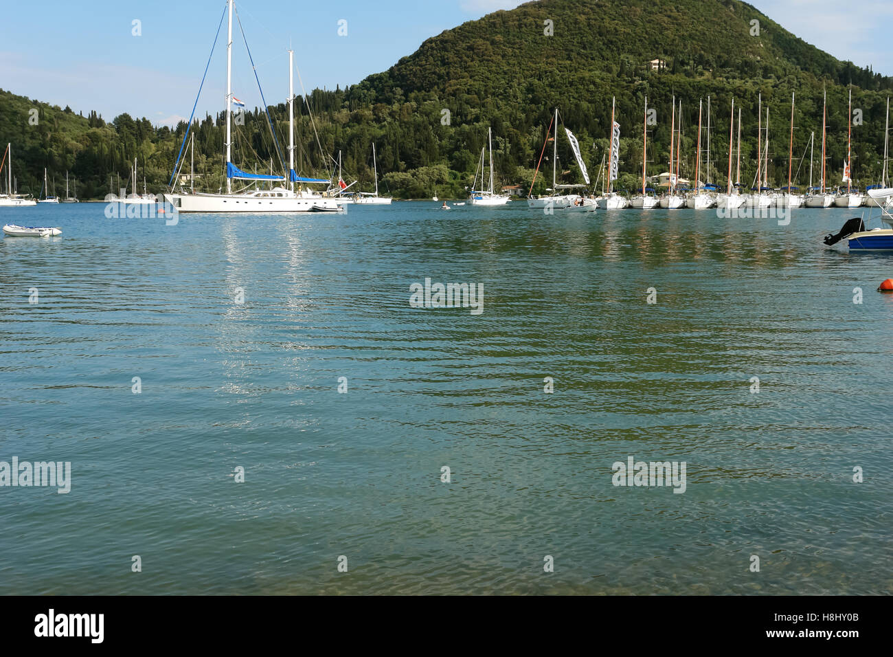 Nidri, Griechenland, 11. Mai 2013: Landschaft mit blauen Hafen, grüne Küste und Yachten im Ionischen Meer, Griechenland. Stockfoto