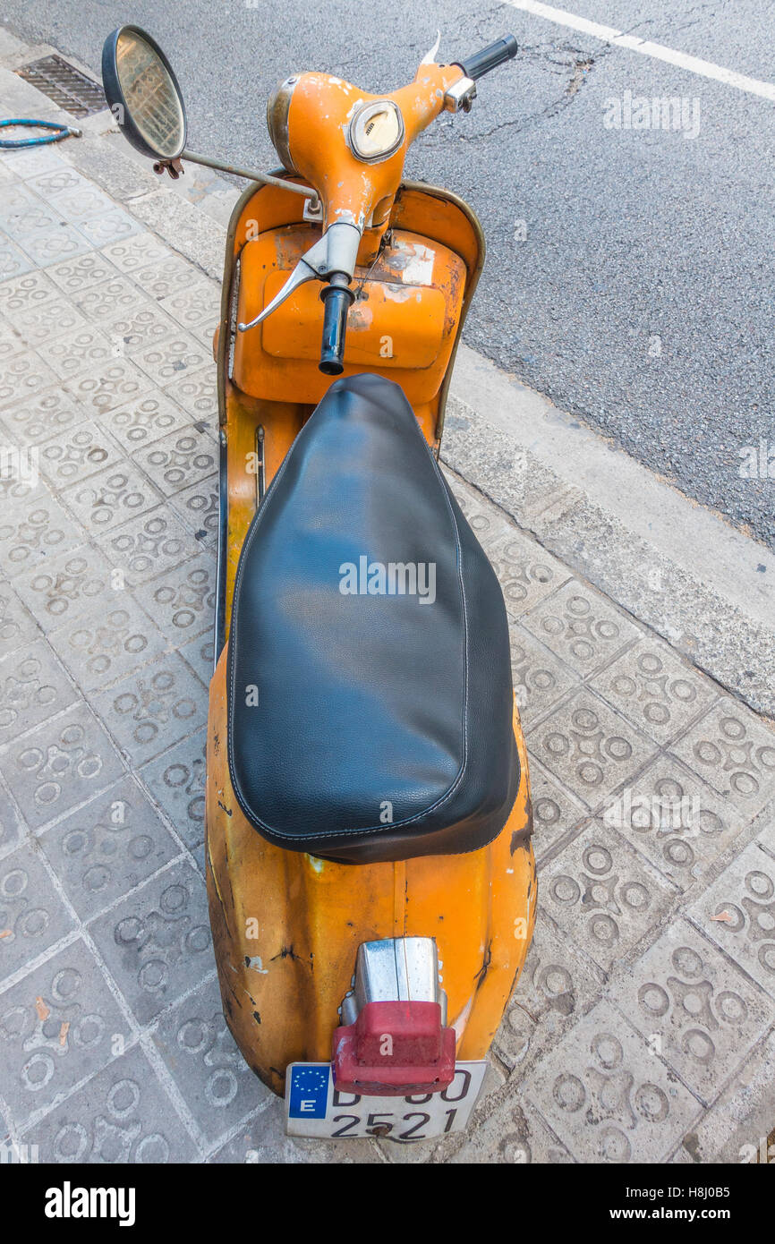 Eine sehr alte orange und schwarz Vespa Super Motorscooter parkt auf einem Bürgersteig in Barcelona, Spanien. Stockfoto