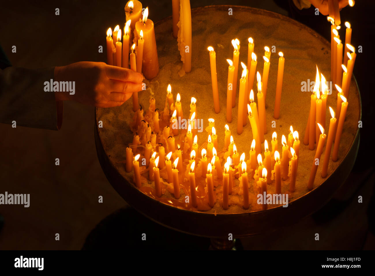 Frau Hand Anzünden von Kerzen in der Kirche Stockfoto