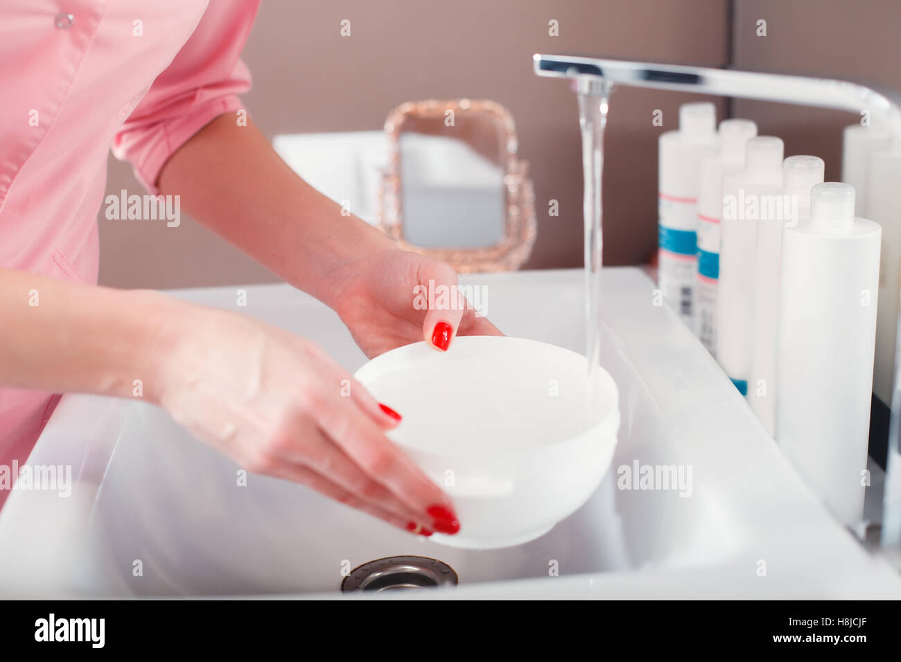 Kosmetischen Schüssel mit Wasser aus dem Wasserhahn befüllen. Stockfoto