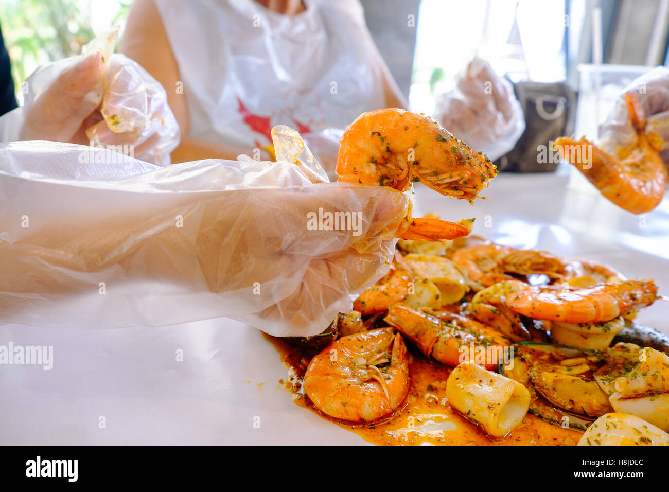 Krustentier Meeresfrüchte Muscheln, Austern und Garnelen mit Hand am Tisch und weiß Wachspapier, Tiefenschärfe, Essen Hintergrund. Stockfoto