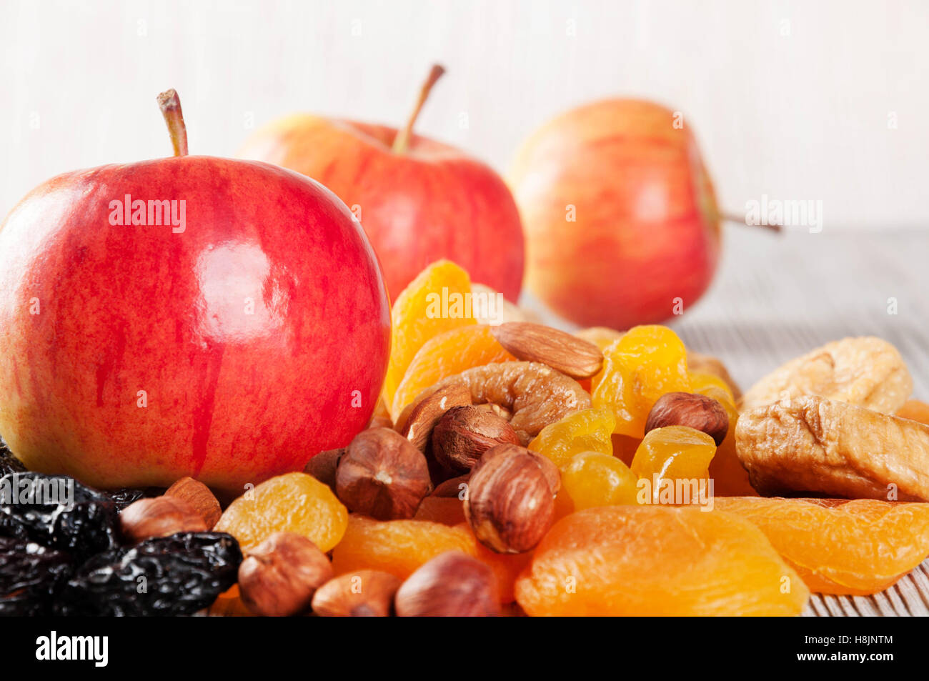Reife rote Äpfel auf einem hölzernen Hintergrund. Saftige Äpfel, Nüssen und getrockneten Früchten auf einem Tisch. Stockfoto