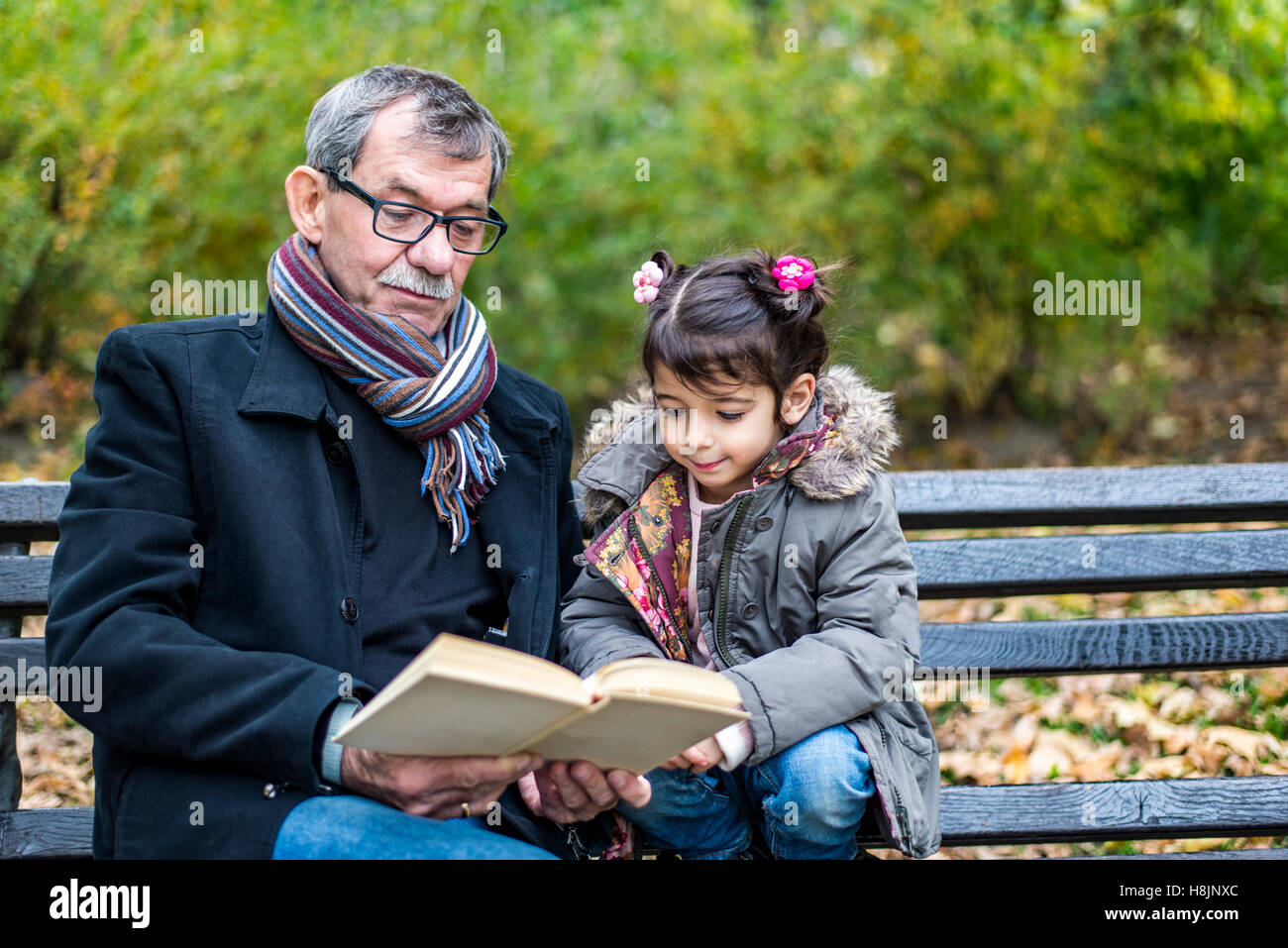 Großvater und Enkelin Lesen eines Buches im Herbst park Stockfoto