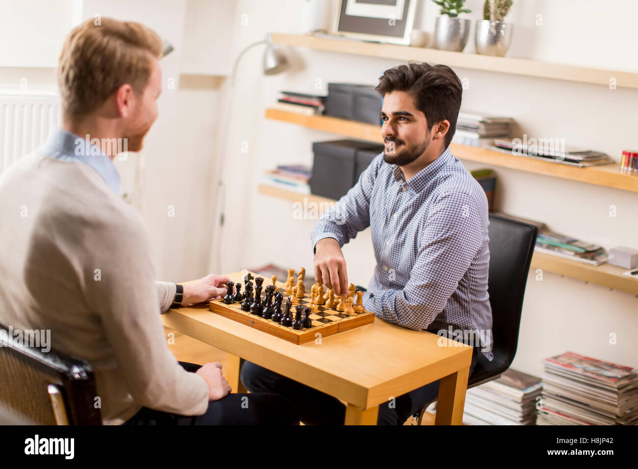 Zwei junge Männer spielen Schach im Zimmer Stockfoto