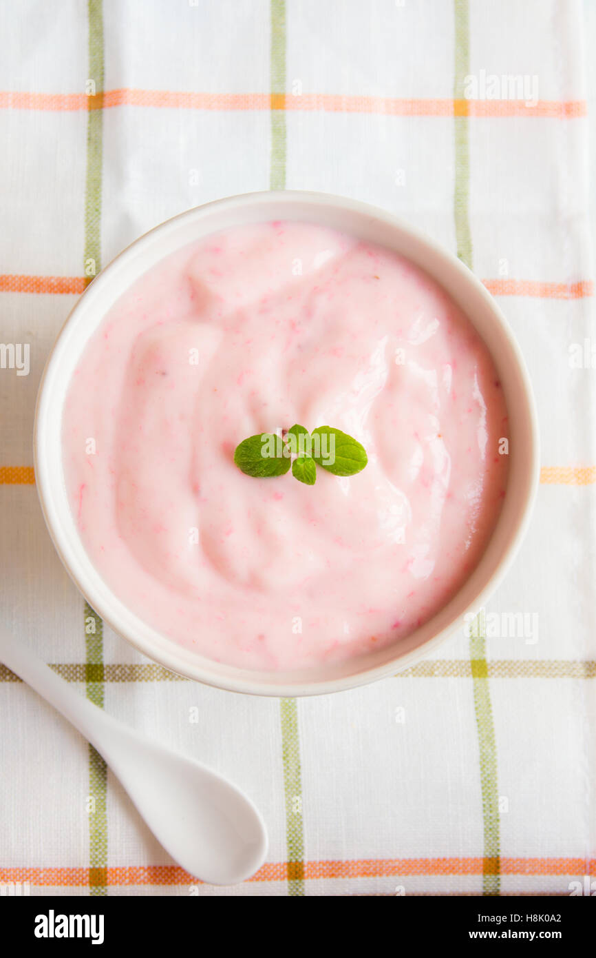 Erdbeer-Joghurt mit Minze auf hölzernen weißen Hintergrund. Erdbeer Joghurt. Rosa Joghurt. Stockfoto