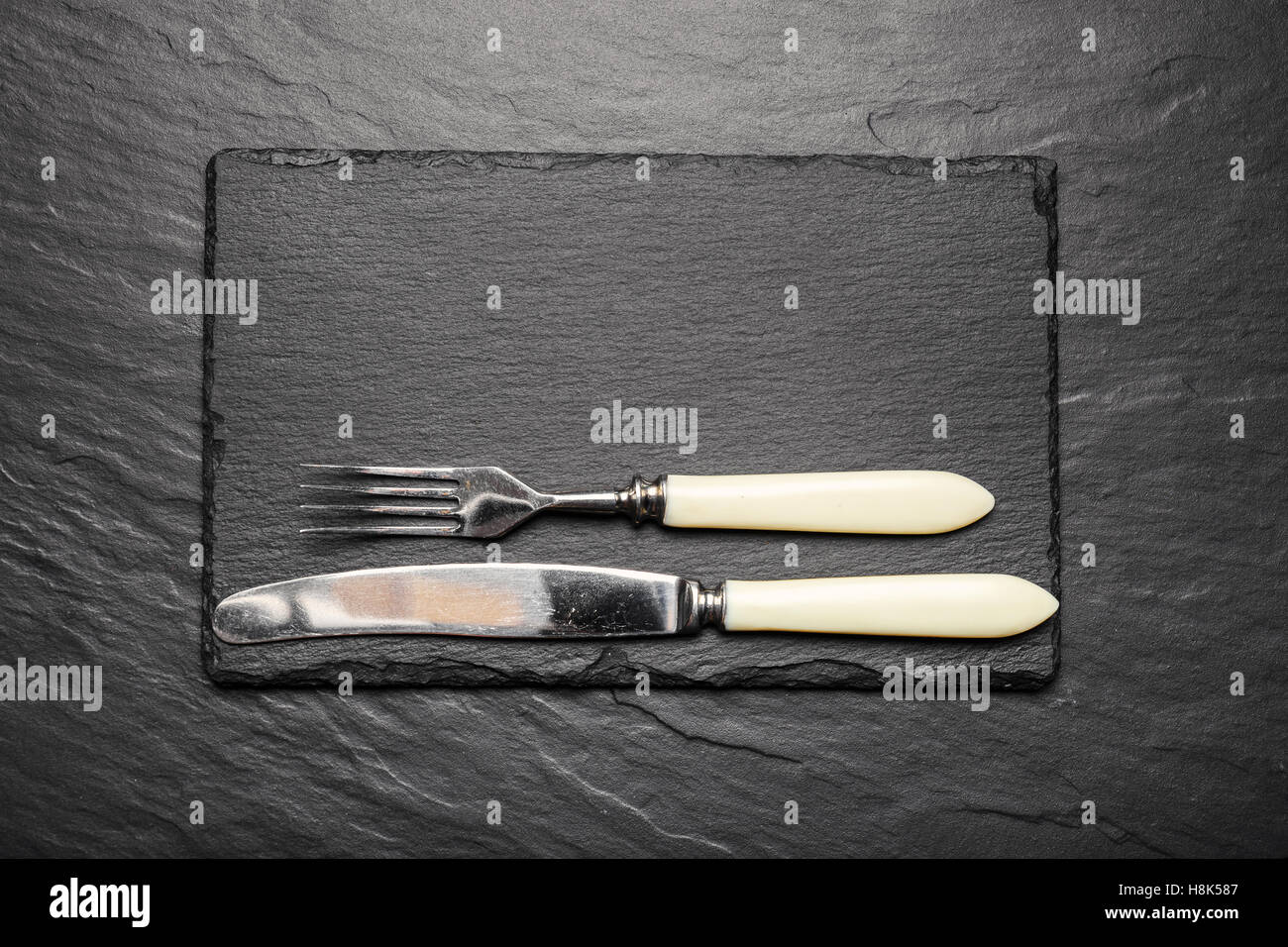 Schiefer Tafel zum Servieren mit Gabel und Messer, Ansicht von oben Stockfoto