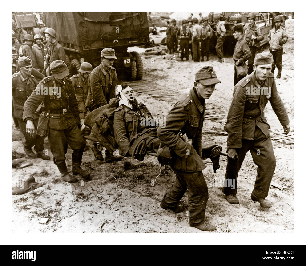 NAZI-VERWUNDETE GEFANGENE D-Day Operation Overlord WW2 deutsche Kriegsgefangene bringen verwundete Kameraden auf ein Landungsschiff an einem Strand der Normandie mit amerikanischen Truppen hinter June1944 Nordfrankreich Stockfoto