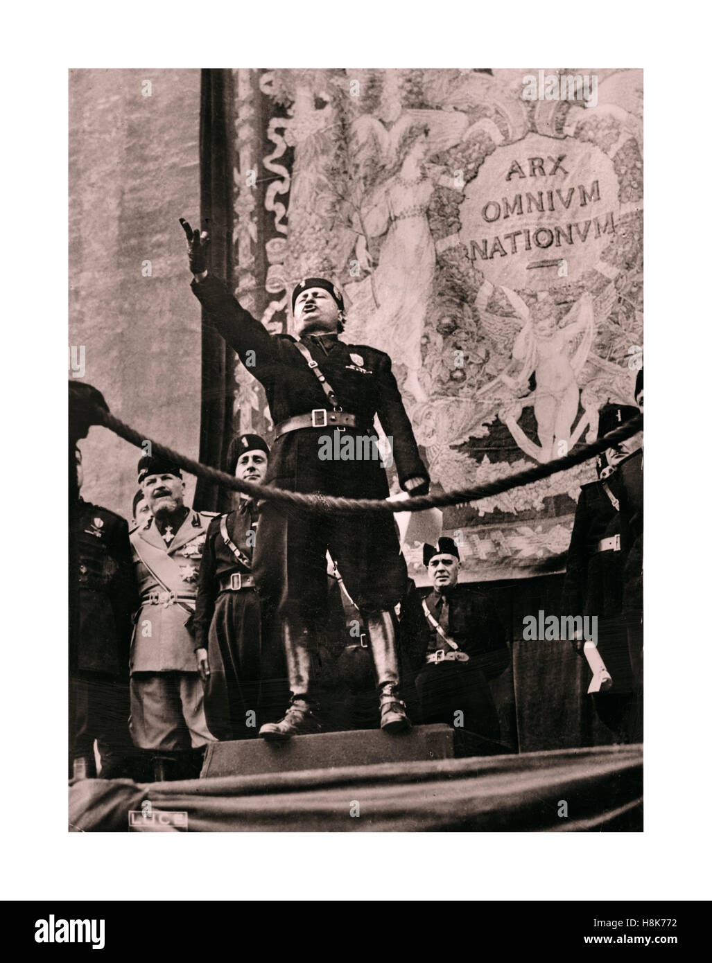 Benito Mussolini, Italienisch facist Diktator, in voller oratorischen Flow mit einer Masse in Rom mit einem Wandteppich hinter Lesen "arx omnium nationum" das Zentrum aller Nationen... (Cicero) Sitz des Römischen Reiches 1930 2.Weltkrieg ära Stockfoto
