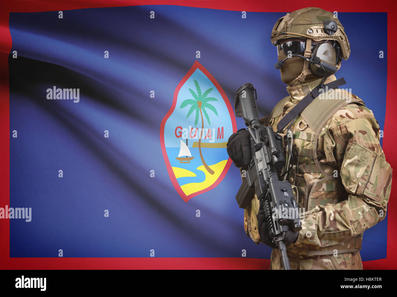 Soldat im Helm holding Maschinengewehr mit Nationalflagge auf Hintergrund - Guam Stockfoto