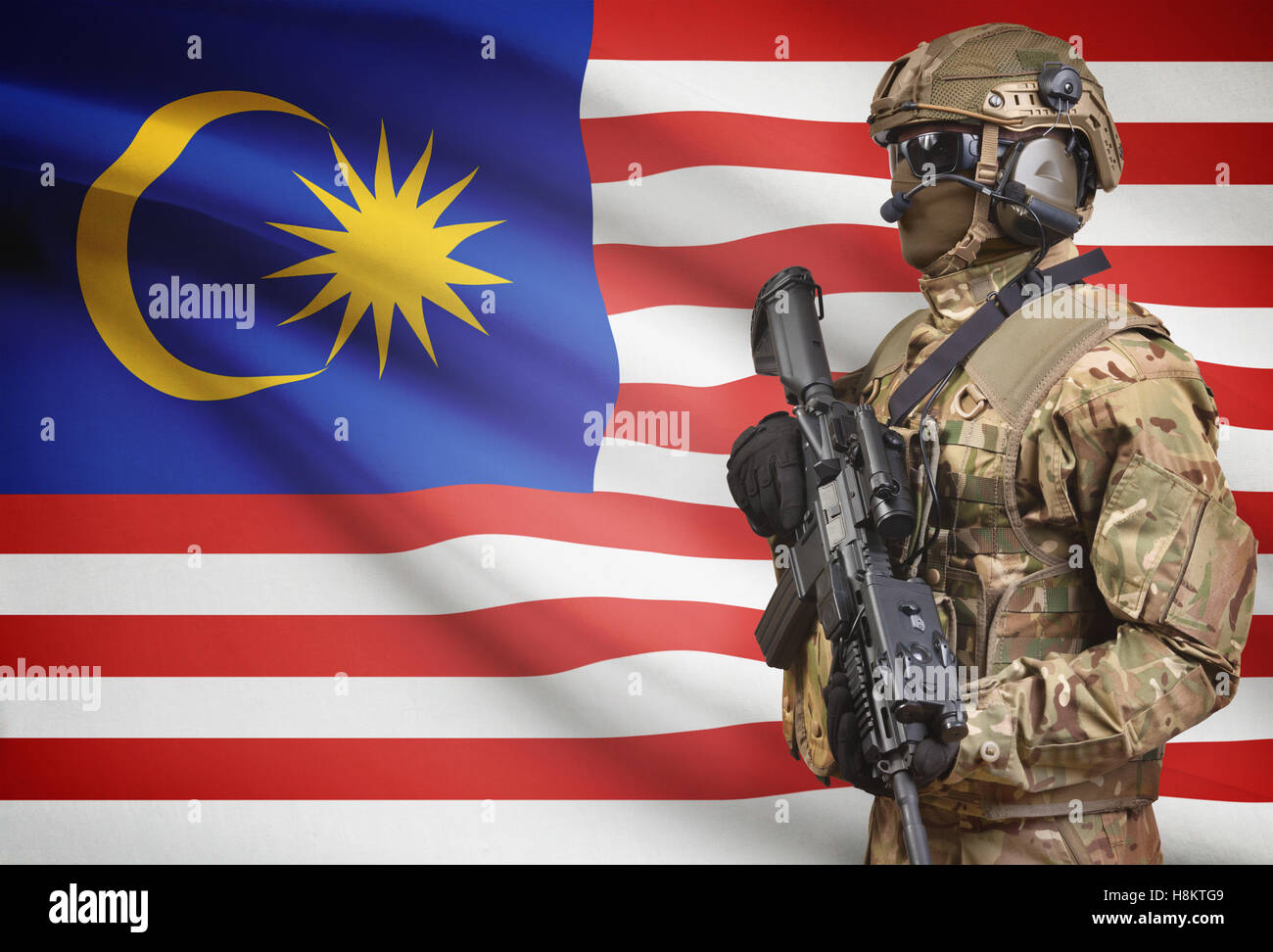 Soldat im Helm holding Maschinengewehr mit Nationalflagge auf Hintergrund - Malaysia Stockfoto