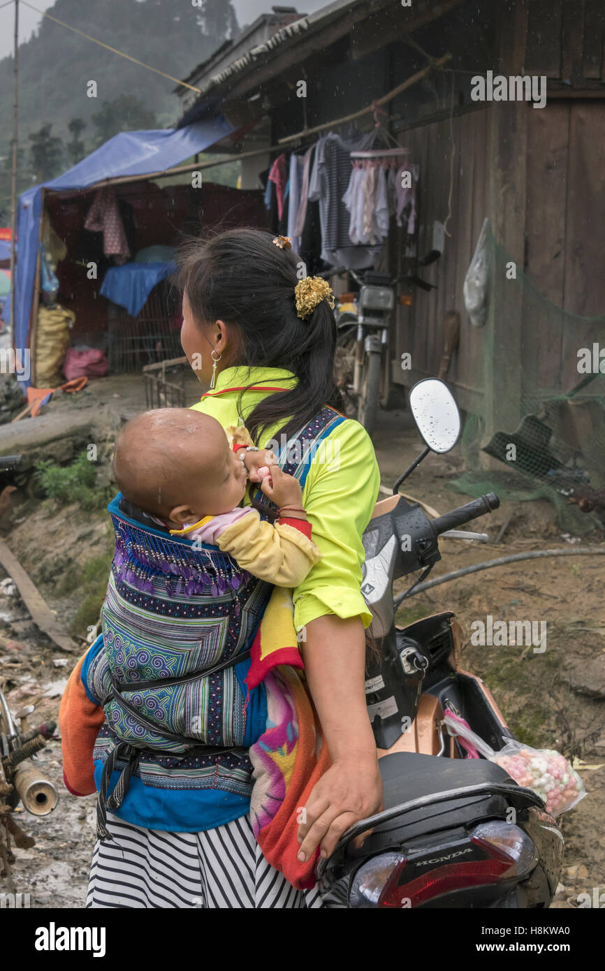Hmong-Mutter und Baby von Motorrad an einem regnerischen Tag, Coc Ly Markt in der Nähe von Sa Pa, Nord-Vietnam Stockfoto