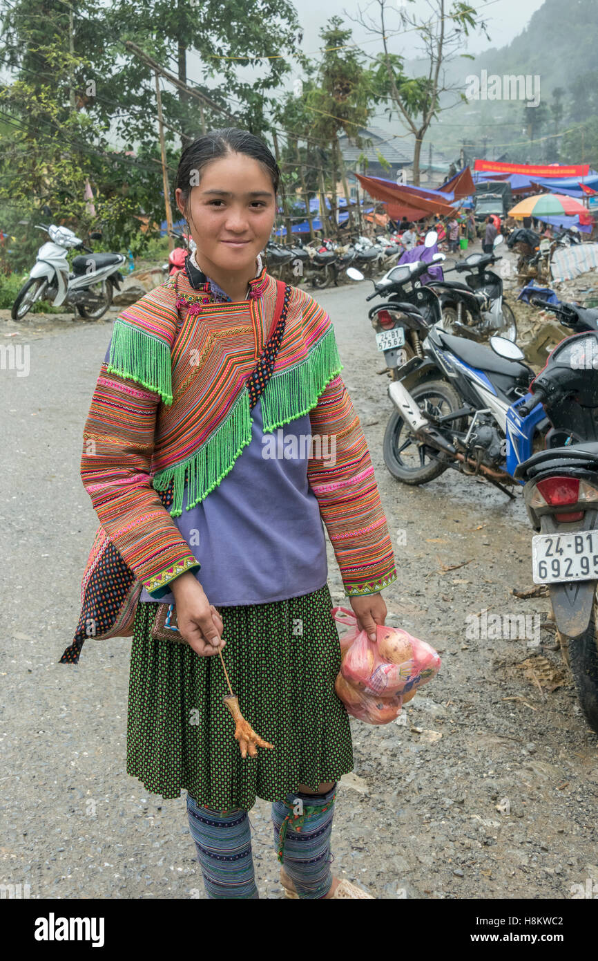 Hmong Blumenmädchen mit einem Brathähnchen Fuß, Coc Ly Markt in der Nähe von Sa Pa, Nord-Vietnam Stockfoto