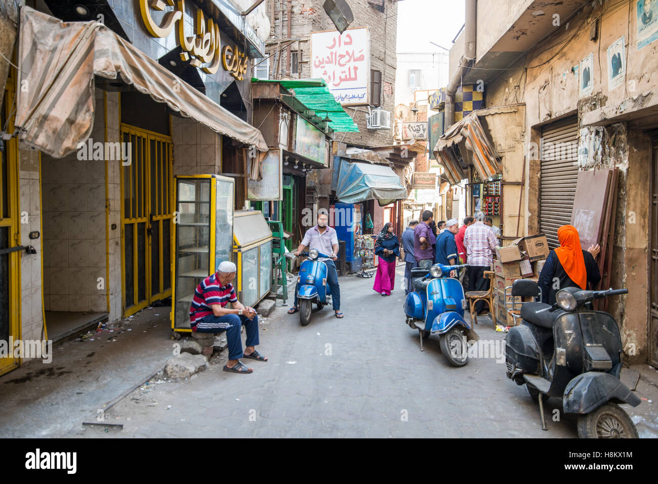 Kairo, Ägypten. Einheimische fahren motor Roller und zu Fuß durch eine Gasse in der Outdoor-Basar / Flohmarkt Khan el-Khalili ich Stockfoto