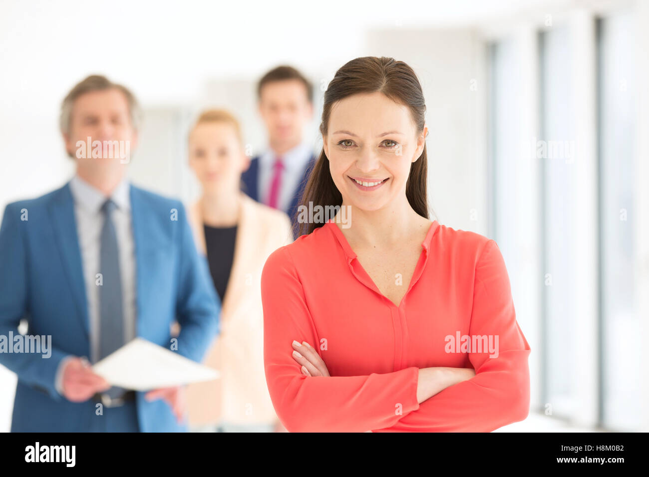 Porträt von zuversichtlich Geschäftsfrau mit Team im Hintergrund im Büro Stockfoto