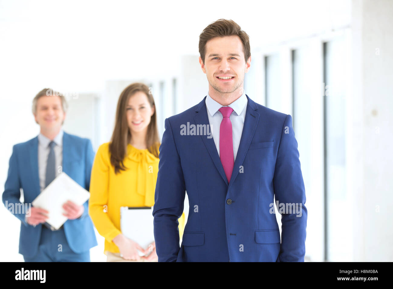 Porträt von zuversichtlich junger Geschäftsmann mit Team im Hintergrund im Büro Stockfoto