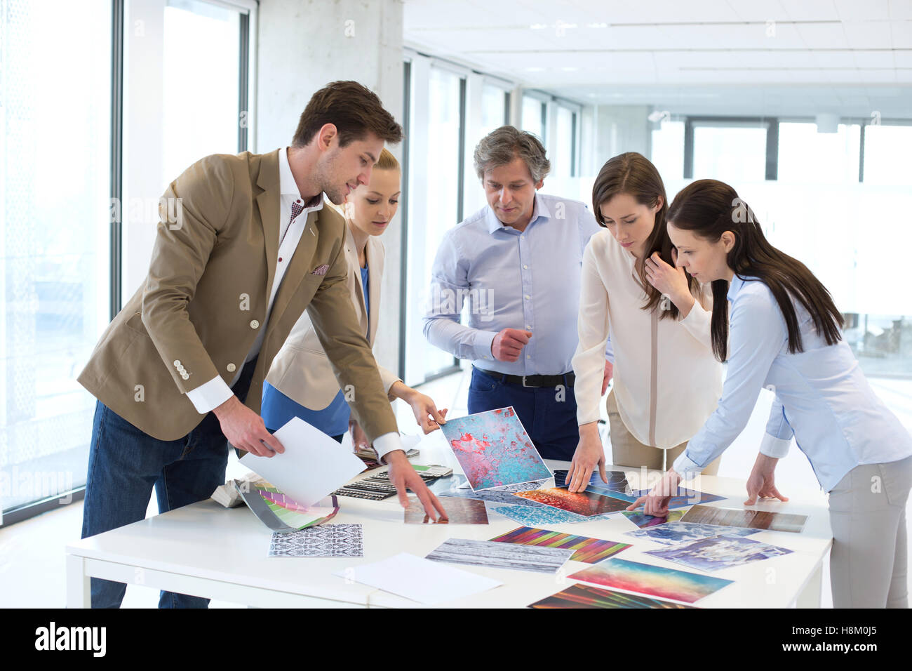 Design-Profis mit Katalogen mit Diskussion am Tisch im neuen Büro Stockfoto