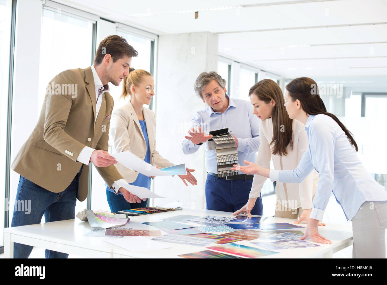 Design-Profis mit Katalogen diskutieren am Tisch im neuen Büro Stockfoto