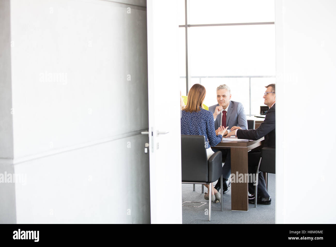 Unternehmer und Unternehmerin im Sitzungsraum gesehen durch offene Tür im Büro Stockfoto