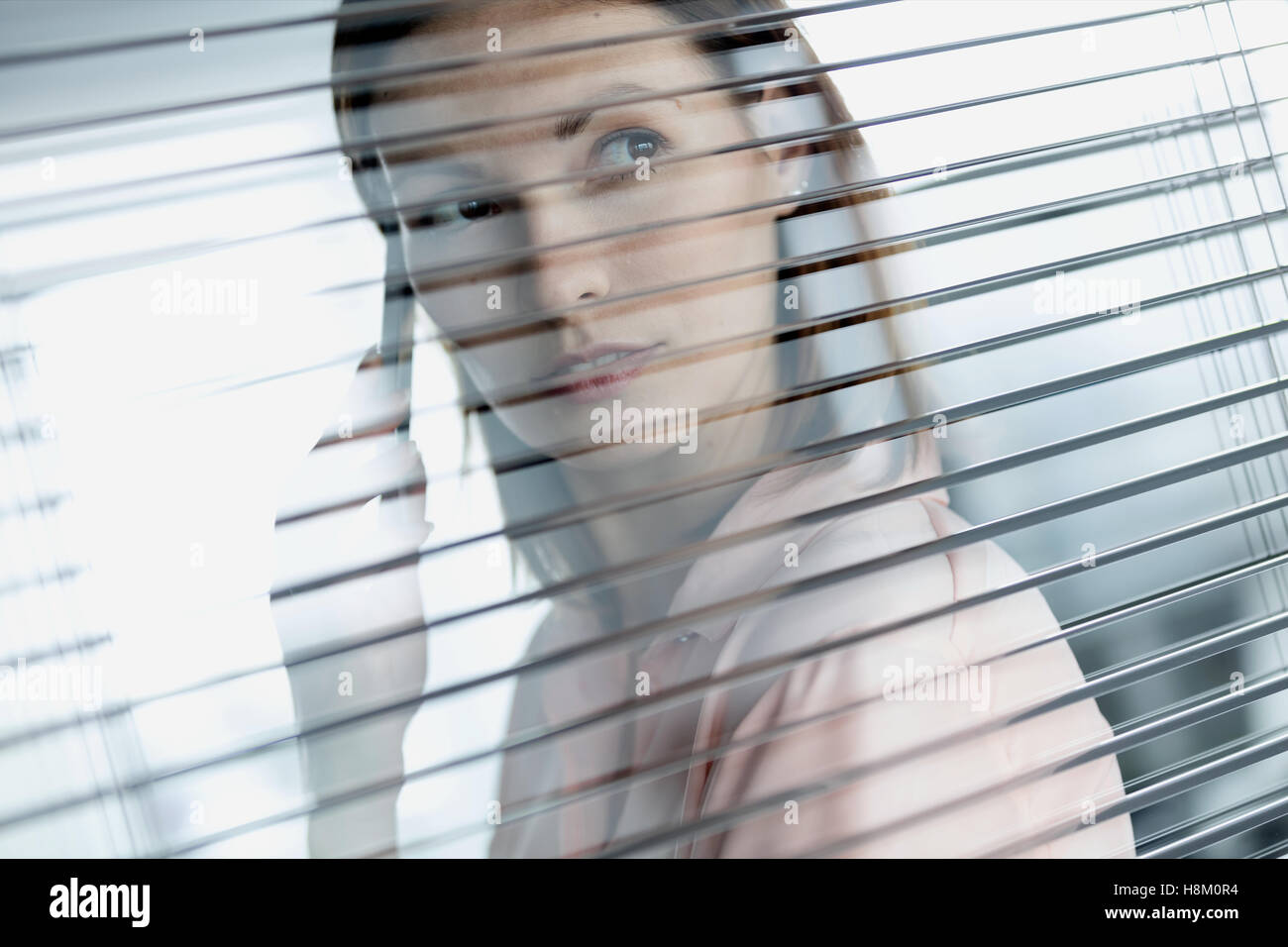 Nahaufnahme der junge Geschäftsfrau mit Handy während der Blick aus dem Bürofenster Stockfoto