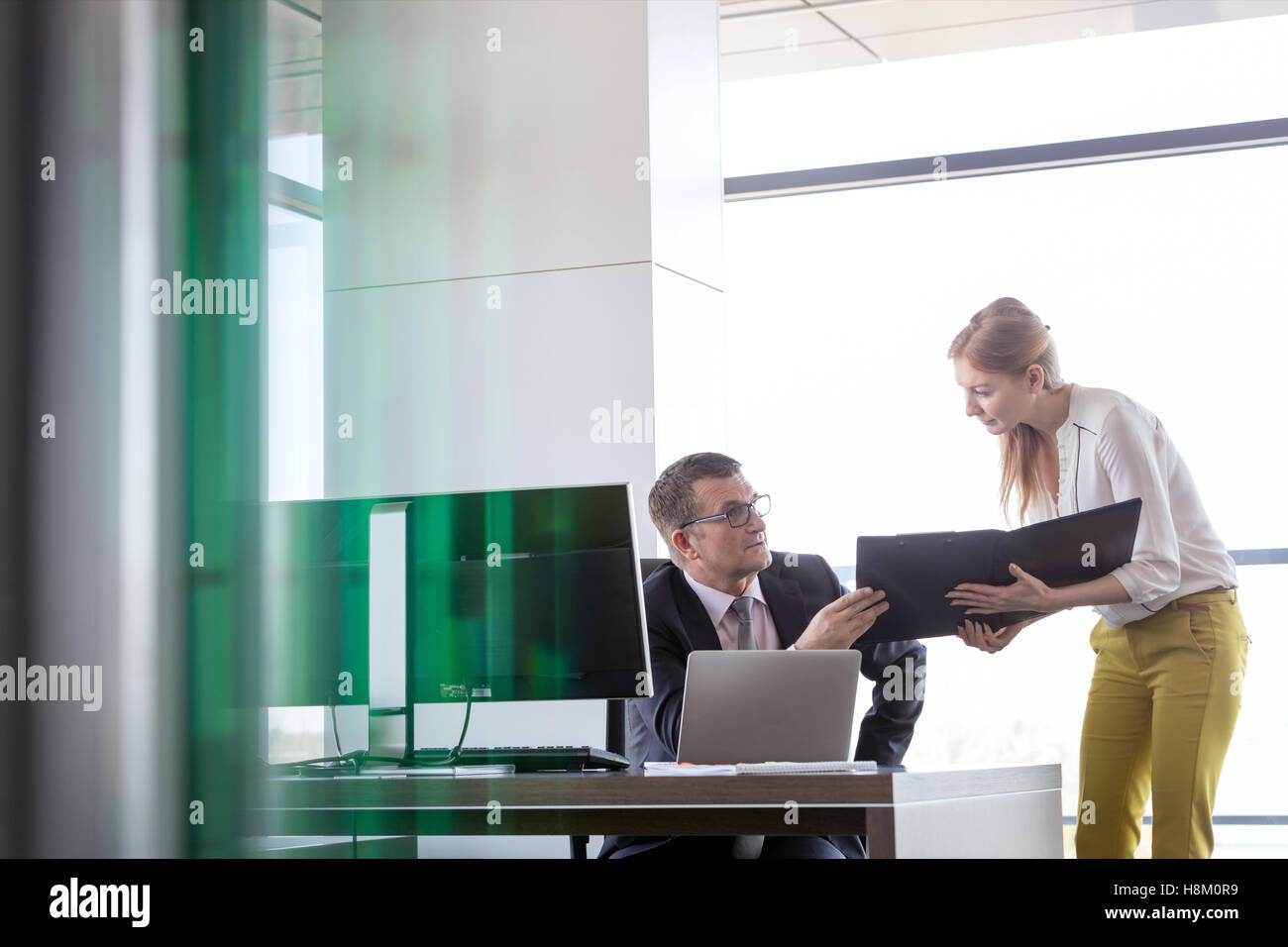 Geschäftsfrau zeigt Datei Geschäftsmann am Schreibtisch im Büro Stockfoto