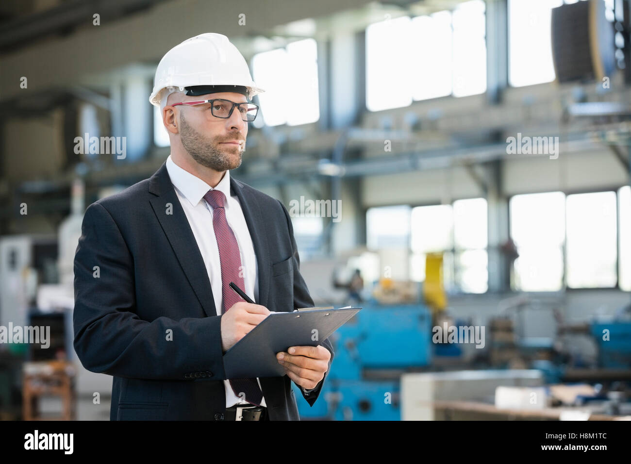 Mitte adult Geschäftsmann schreiben über Zwischenablage in der Metallbranche Stockfoto