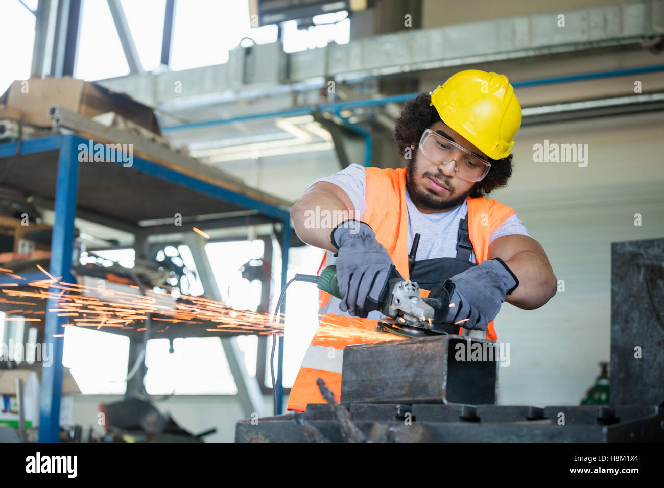 Junge Arbeiter in Schutzkleidung Schneiden von Metall in der Industrie Stockfoto