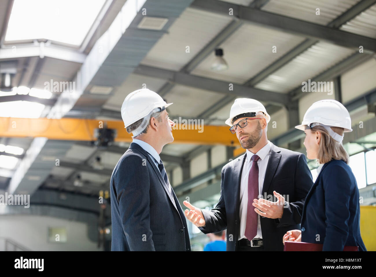 Business-Leute tragen Schutzhelme mit Diskussion in der Metallbranche Stockfoto