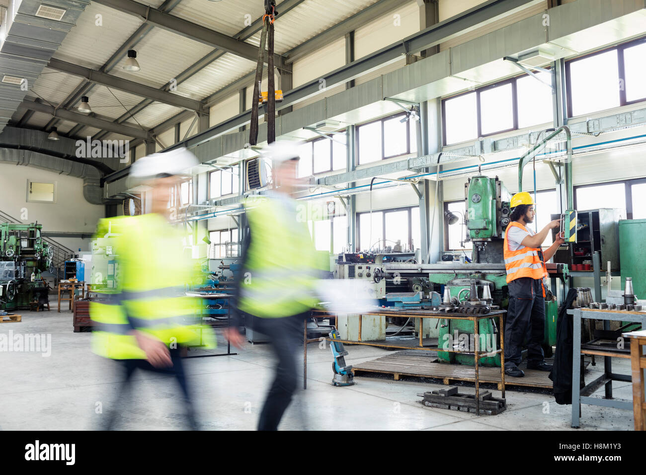 Bewegungsunschärfe von Geschäftsleuten zu Fuß mit Arbeiter im Hintergrund bei industry Stockfoto