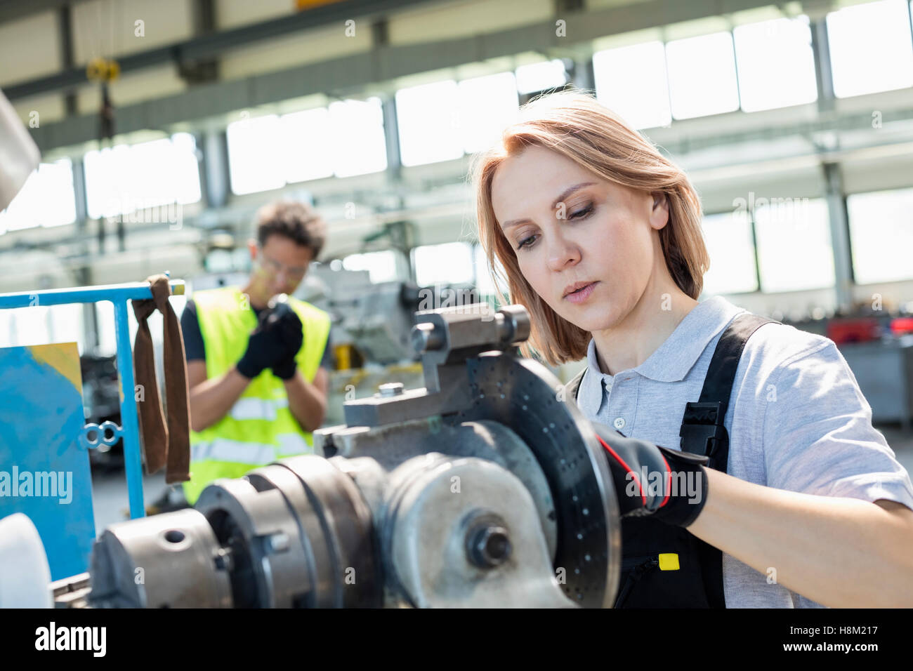 Ältere Arbeitnehmerin arbeiten an Maschinen mit Kollegen im Hintergrund bei industry Stockfoto