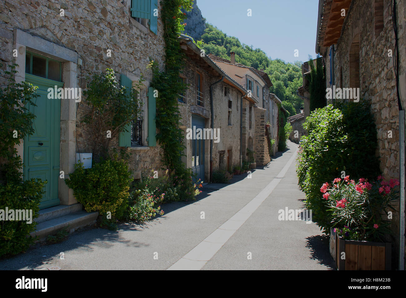 Schmale Stein gepflasterter Straße im ländlichen Frankreich mit seinen grünen, Topfpflanzen und Blumen bunt selbst ausgesät Stockfoto
