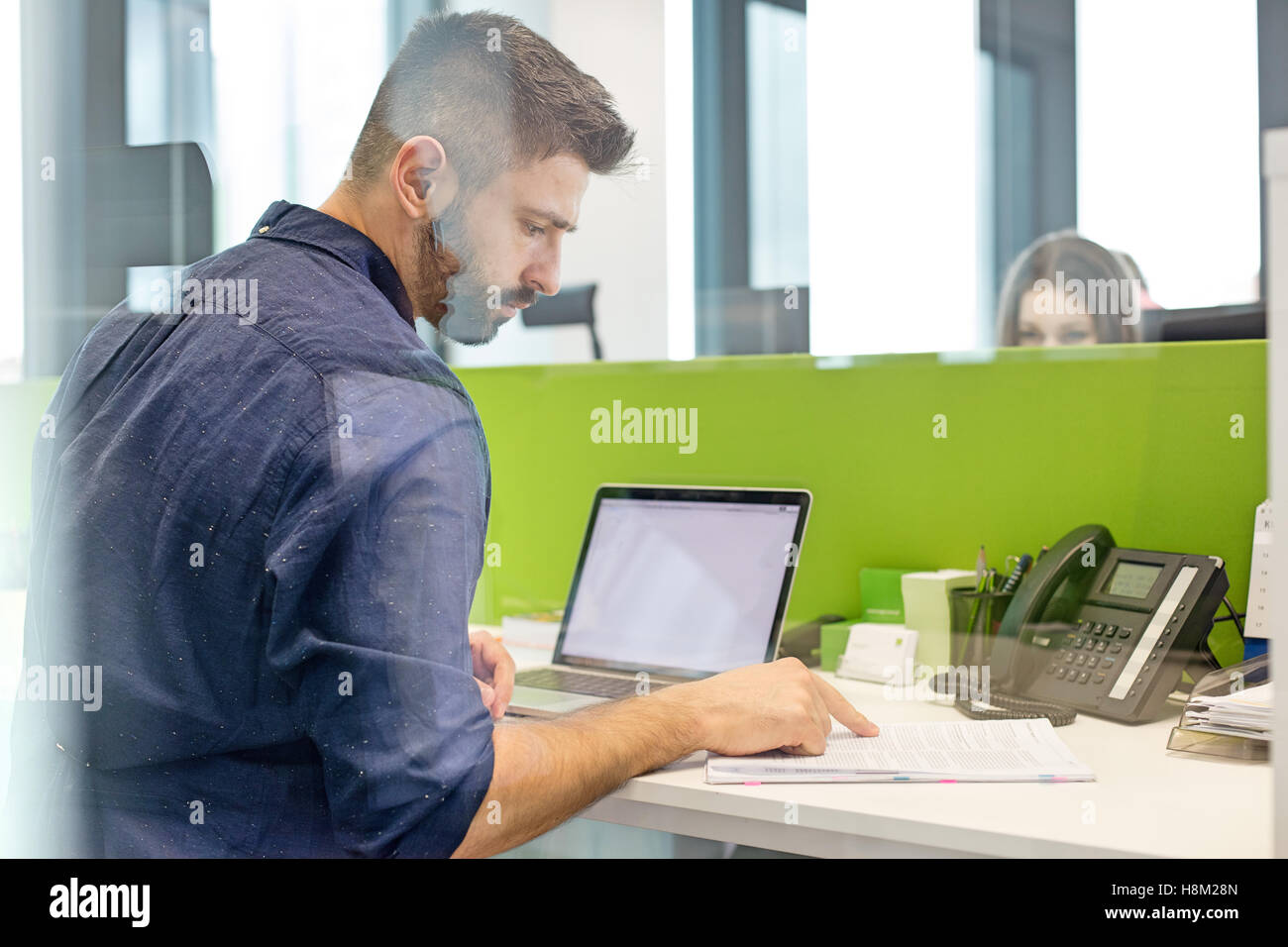 Mitte adult Geschäftsmann mit Laptop Buch am Schreibtisch im Büro Stockfoto