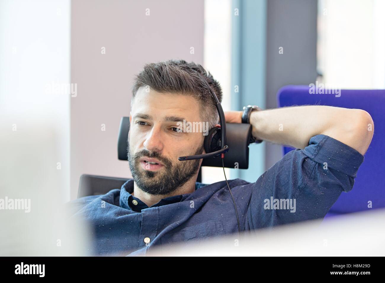 Mitte adult Geschäftsmann Telefon Kopfhörer im Büro tragen Stockfoto