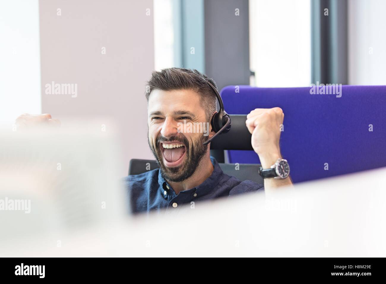 Erfolgreiche Mitte adult Geschäftsmann tragen Kopfhörer beim ballte die Fäuste im Büro Stockfoto