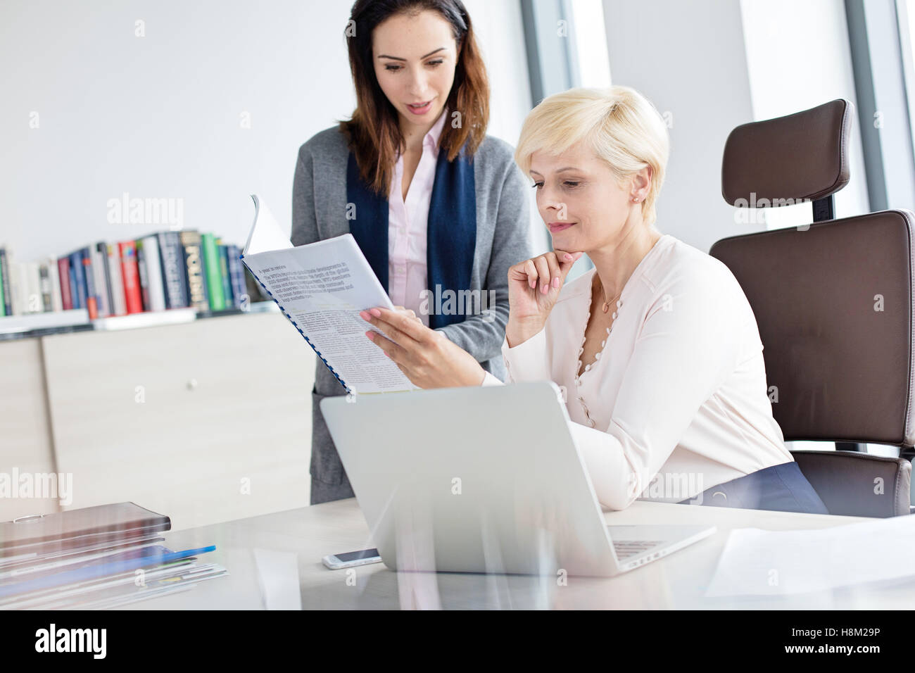 Geschäftsfrau mit Managerin Lesebuch am Schreibtisch im Büro Stockfoto