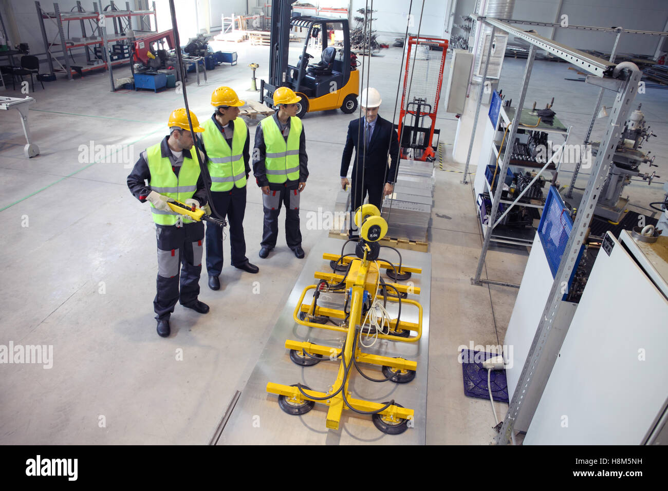 Manager und Arbeitnehmer, die mit Blech Hebevorrichtung in CNC-Fabrik Stockfoto Manager und Arbeitnehmer, die mit Blech Hebevorrichtung in CNC-Fabrik Stockfoto