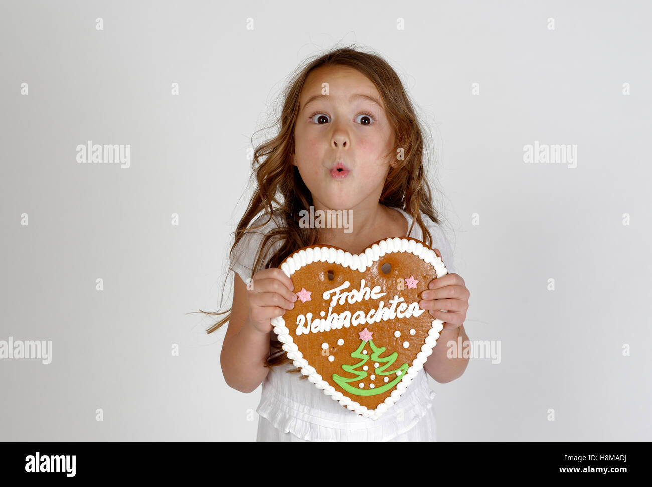 Erstaunt kleines Kind, Mädchen mit Lebkuchen Herz, Frohe Weihnachten, Weihnachtszeit, Deutschland Stockfoto