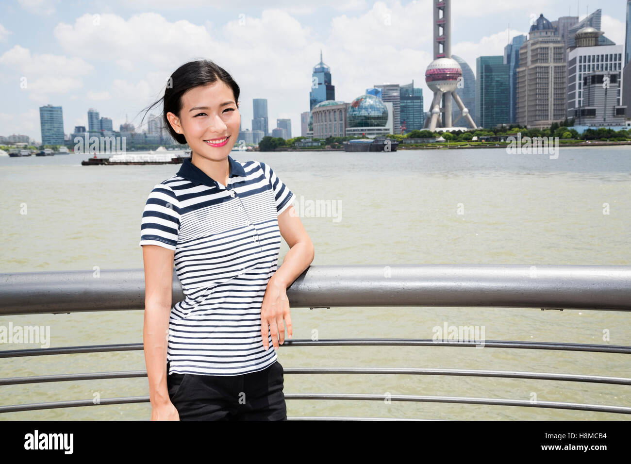 Porträt der Frau stützte sich auf Geländer Fluss mit Oriental Pearl Tower im Hintergrund Stockfoto