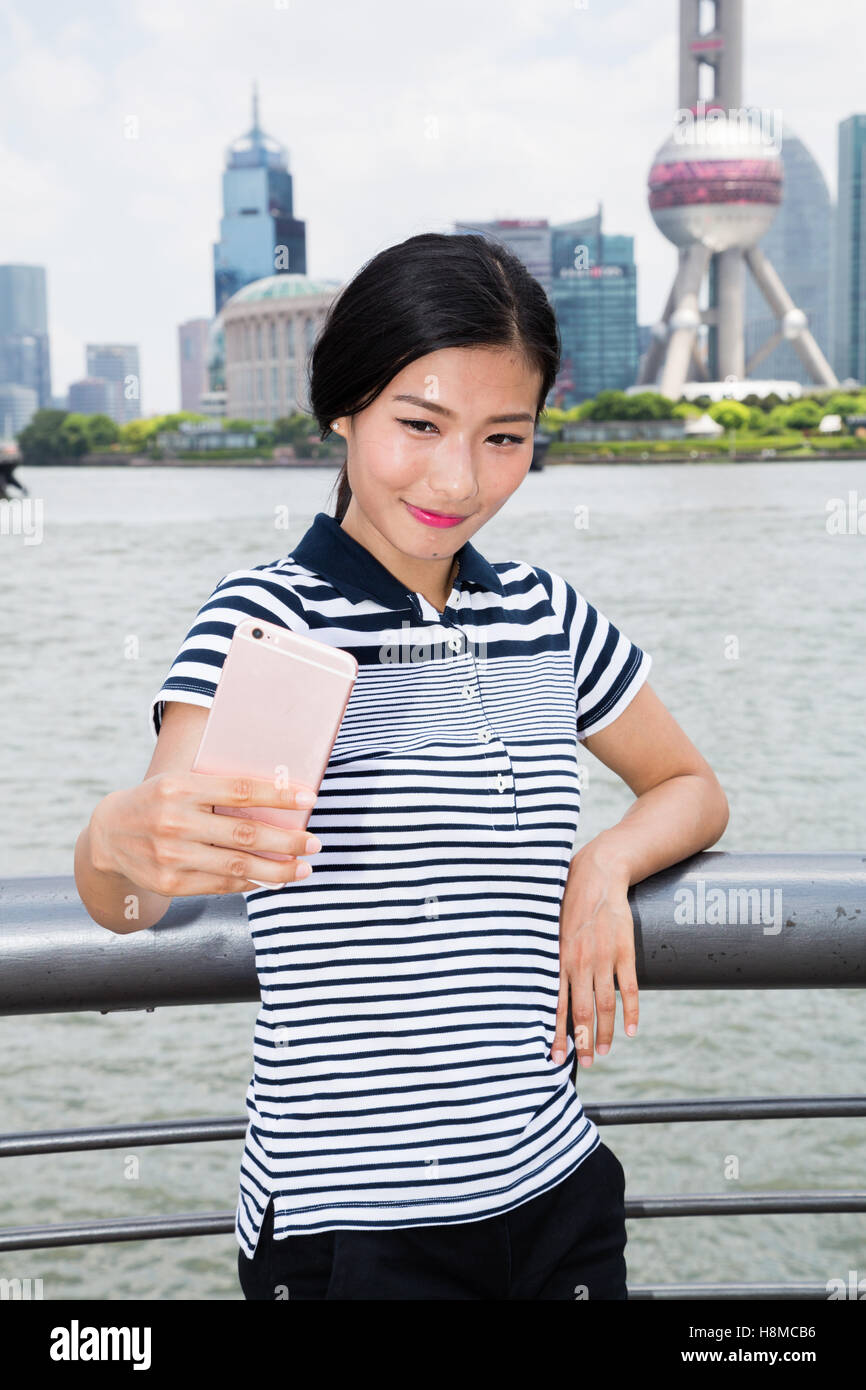 Lächelnde Frau nehmen Selfie durch Smartphone stehend gegen Oriental Pearl Tower Stockfoto