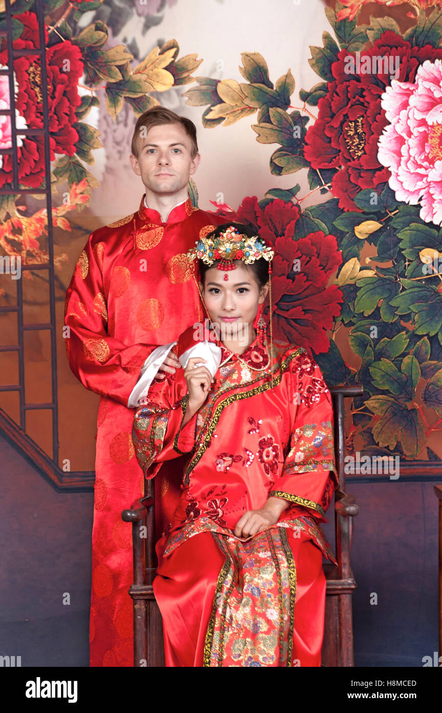 Gemischte Rennen Braut und Bräutigam in Studio tragen traditionelle chinesische Hochzeit outfits Stockfoto