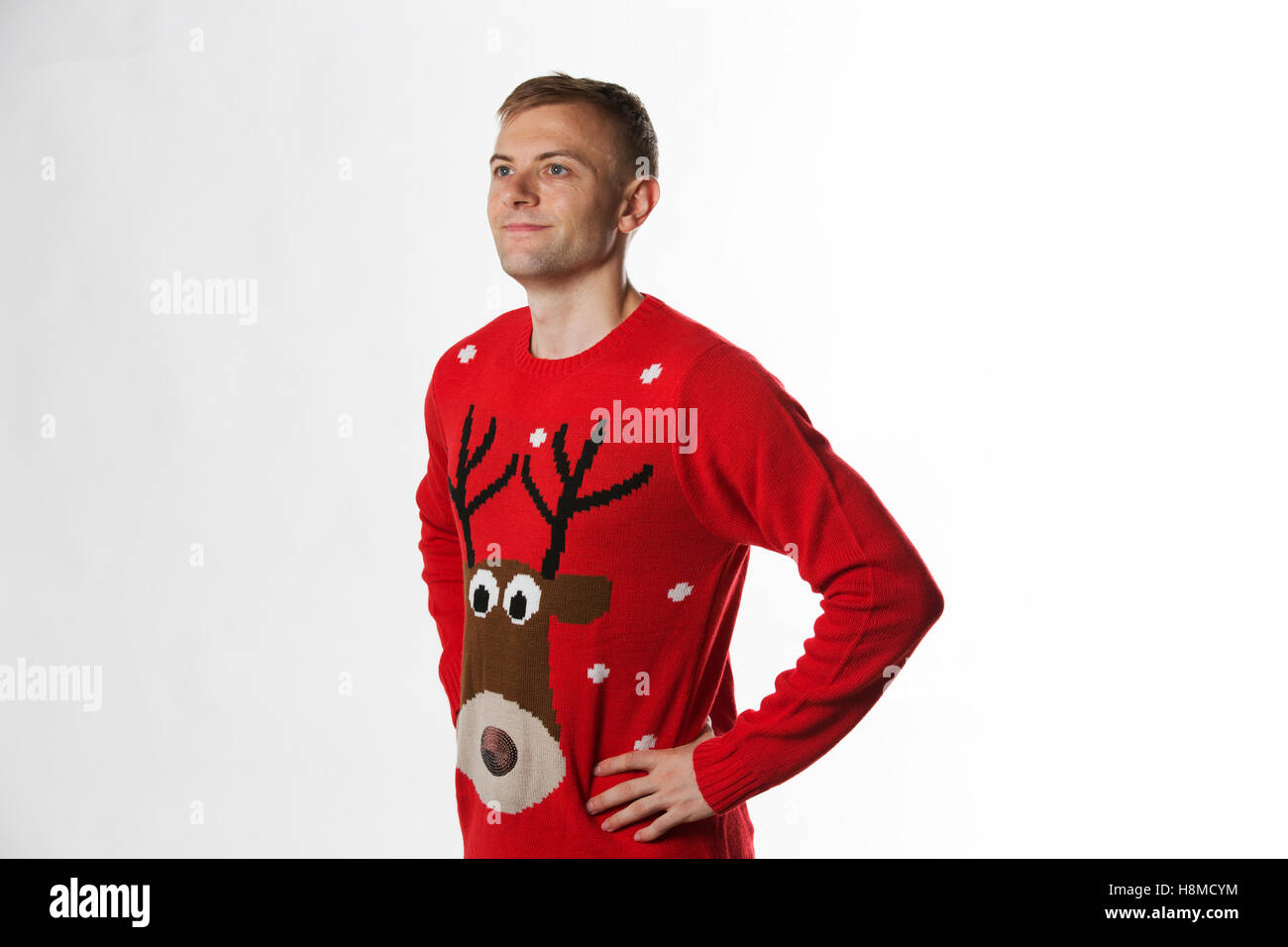 Kaukasischen Mann mit der Hand auf den Hüften, während ein Weihnachtspullover wegsehen von Kamera zu tragen Stockfoto