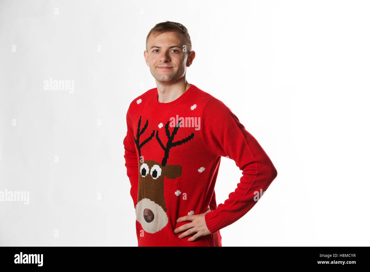 Kaukasischen Mann mit der Hand auf den Hüften, während eine Kamera auf Weihnachtspullover tragen Stockfoto